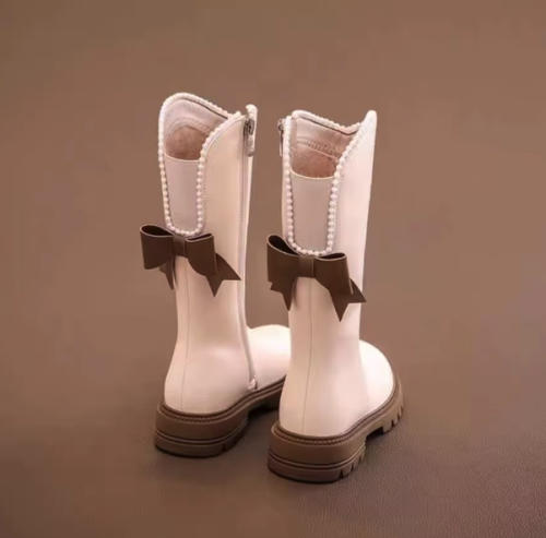 Eleganckie kozaki dla dziewczynki z kokardą i perełkami to modne buty zimowe z wysoką cholewką wykonaną ze skóry ekologicznej, które gwarantują ciepło i wygodę noszenia dzięki praktycznemu zamkowi.