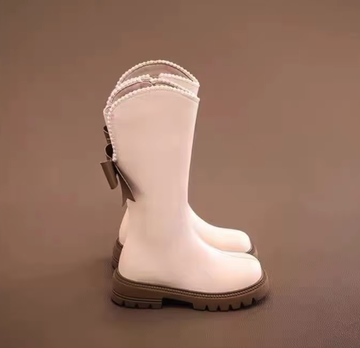 Eleganckie kozaki dla dziewczynki z kokardą i perełkami to modne buty zimowe z wysoką cholewką wykonaną ze skóry ekologicznej, które gwarantują ciepło i wygodę noszenia dzięki praktycznemu zamkowi.