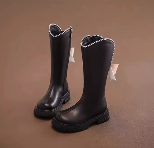 Eleganckie kozaki dla dziewczynki z kokardą i perełkami to modne buty zimowe z wysoką cholewką wykonaną ze skóry ekologicznej, które gwarantują ciepło i wygodę noszenia dzięki praktycznemu zamkowi.